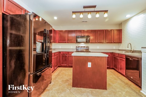 A kitchen with red cabinets and a wooden island.