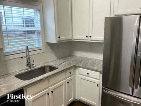 a kitchen with white cabinets and a sink and a refrigerator