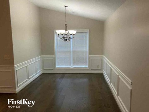 a empty dining room with a large window and a chandelier
