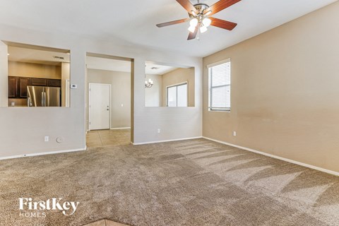 A spacious room with a fan and carpeted floor.