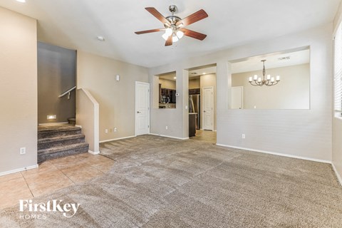 A spacious living room with a carpeted floor and a ceiling fan.
