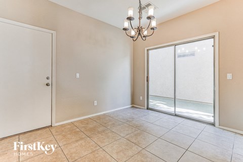 A room with a chandelier, sliding glass doors, and a tiled floor.