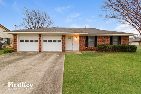 A house with a white garage door and a brick wall.