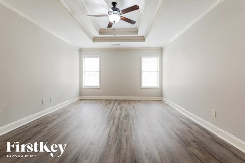 A spacious room with a ceiling fan and wooden flooring.