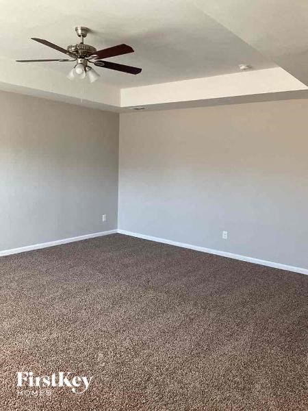 an empty room with a ceiling fan and a carpet