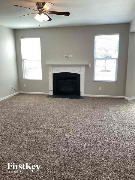 an empty living room with a fireplace and a ceiling fan