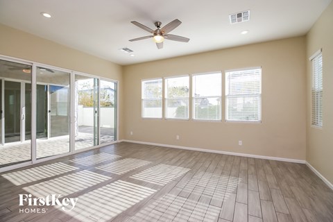an empty living room with a ceiling fan and windows