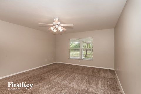 a bedroom with carpet and a ceiling fan and a window
