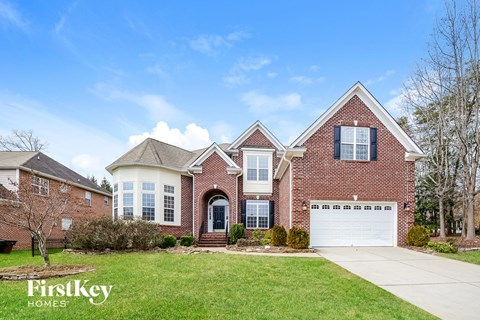 A brick house with a garage and a tree in front.