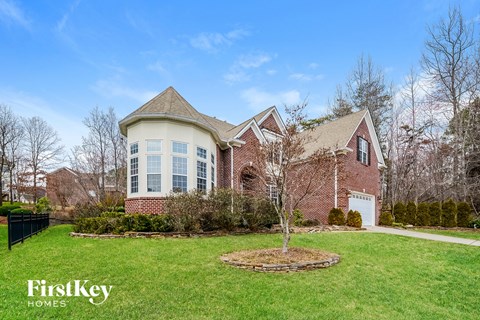 A large house with a well-manicured lawn and a FirstKey Homes logo.