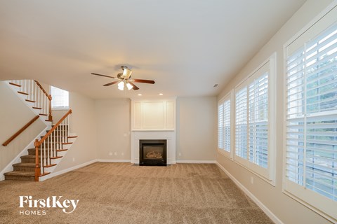 A spacious living room with a fireplace and a staircase.