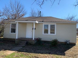 a small tan house with a front porch