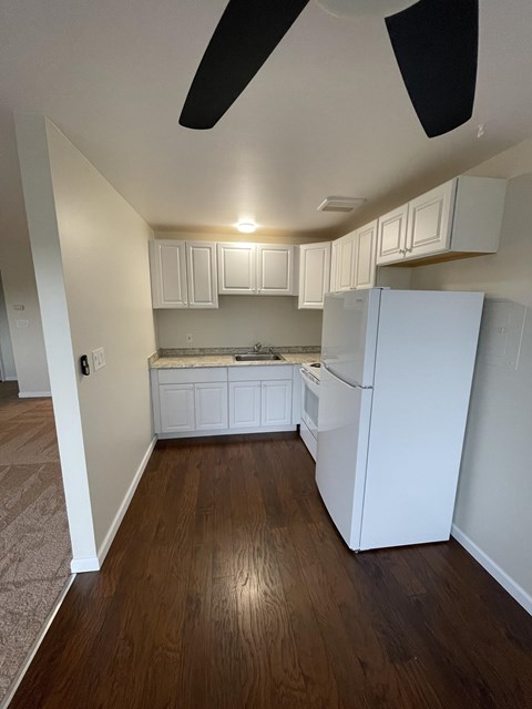 an empty kitchen with white cabinets and a refrigerator