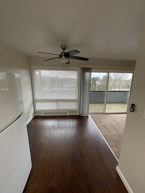 an empty living room with a ceiling fan and a window