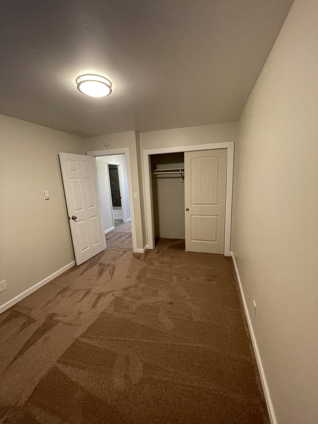 a room with a carpeted hallway and a door to a closet