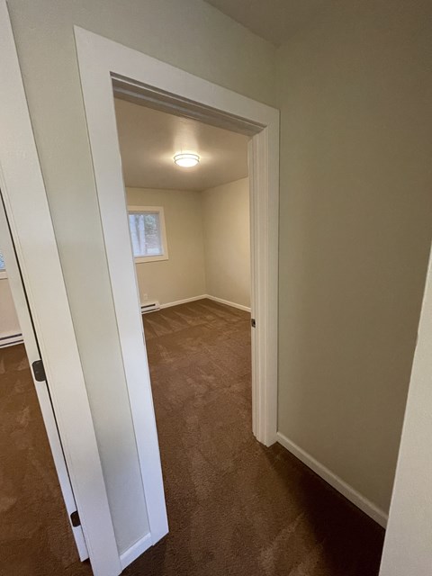 a small room with a door open to a hallway with a window