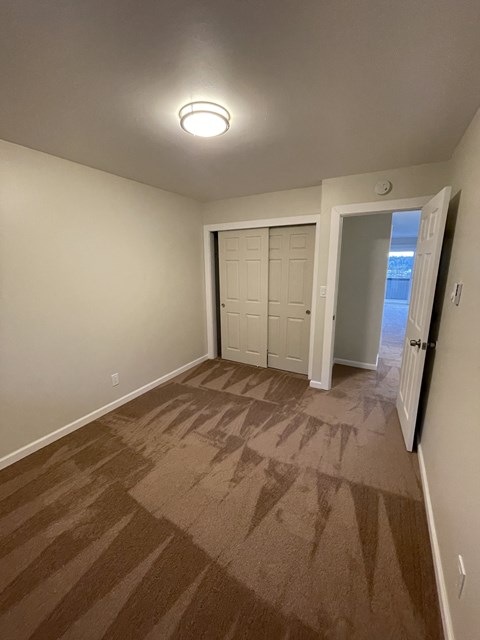 an empty living room with a door to a closet and a door into a bathroom