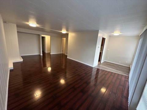 an empty living room with wooden floors and white walls