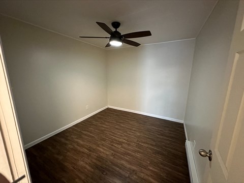 a empty room with wood flooring and a ceiling fan