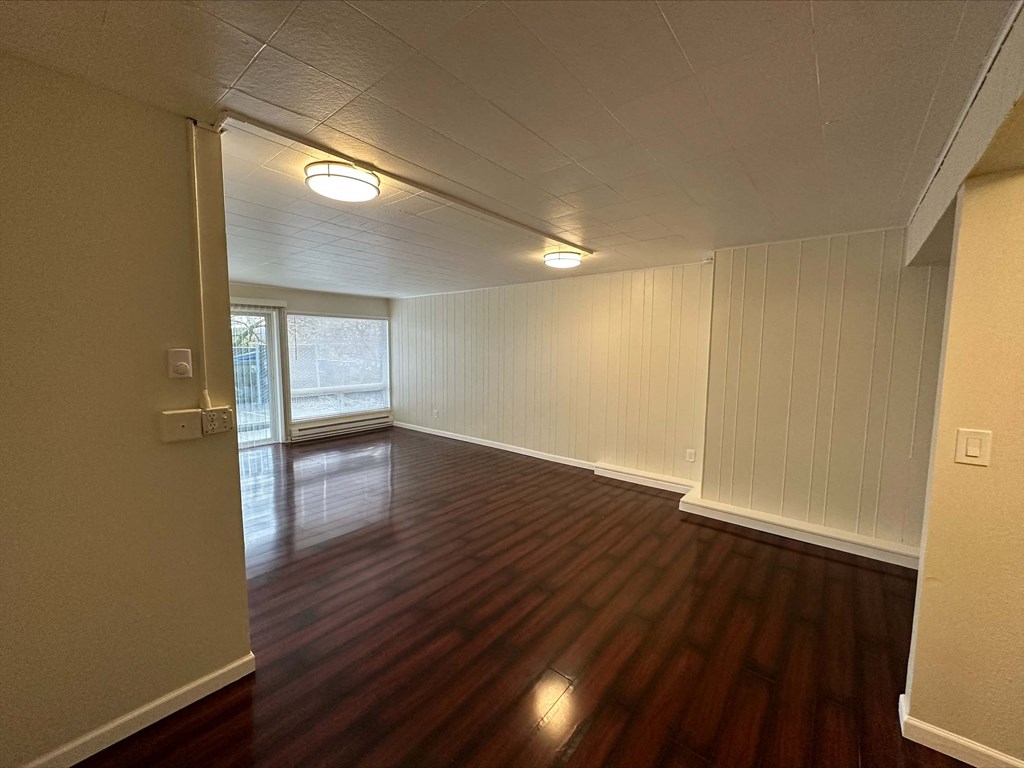 an empty living room with wood floors and a window
