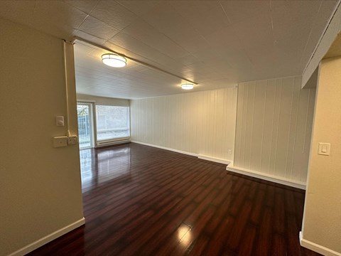 an empty living room with wood floors and a window