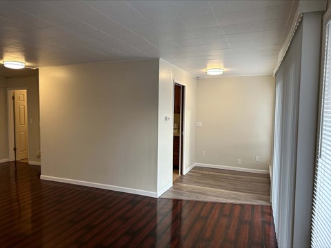 an empty living room with wood floors and white walls
