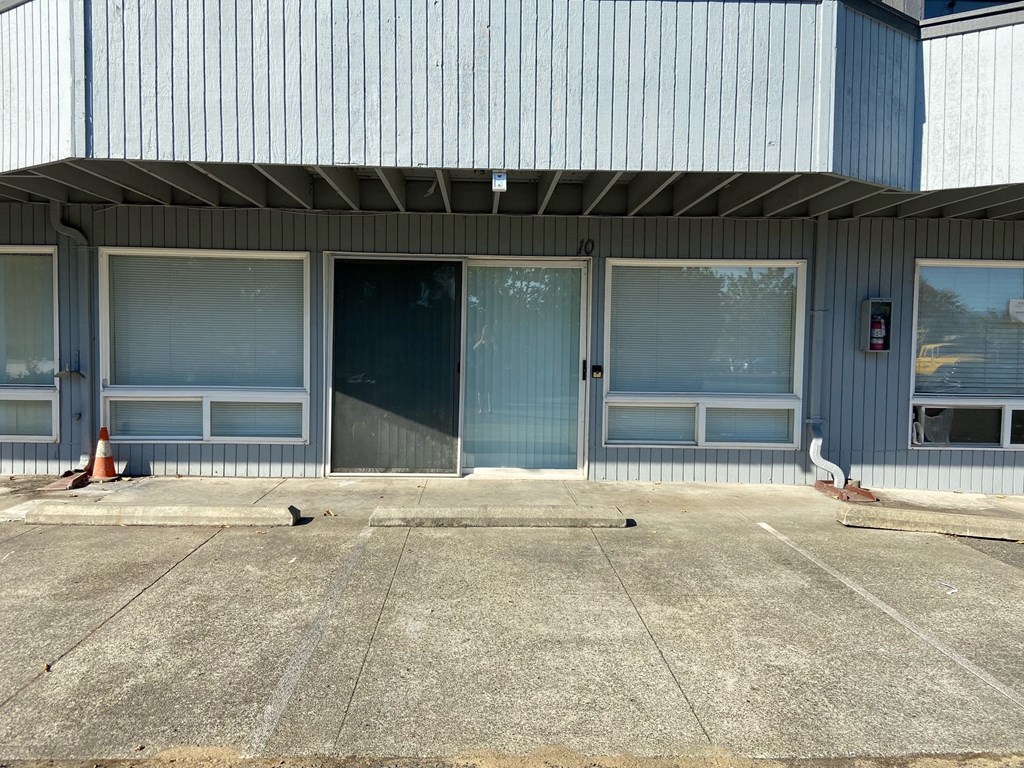 a building with three doors and a sidewalk with pigeons