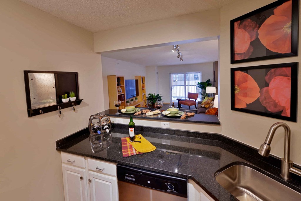 A kitchen with a black counter top and framed pictures on the wall.