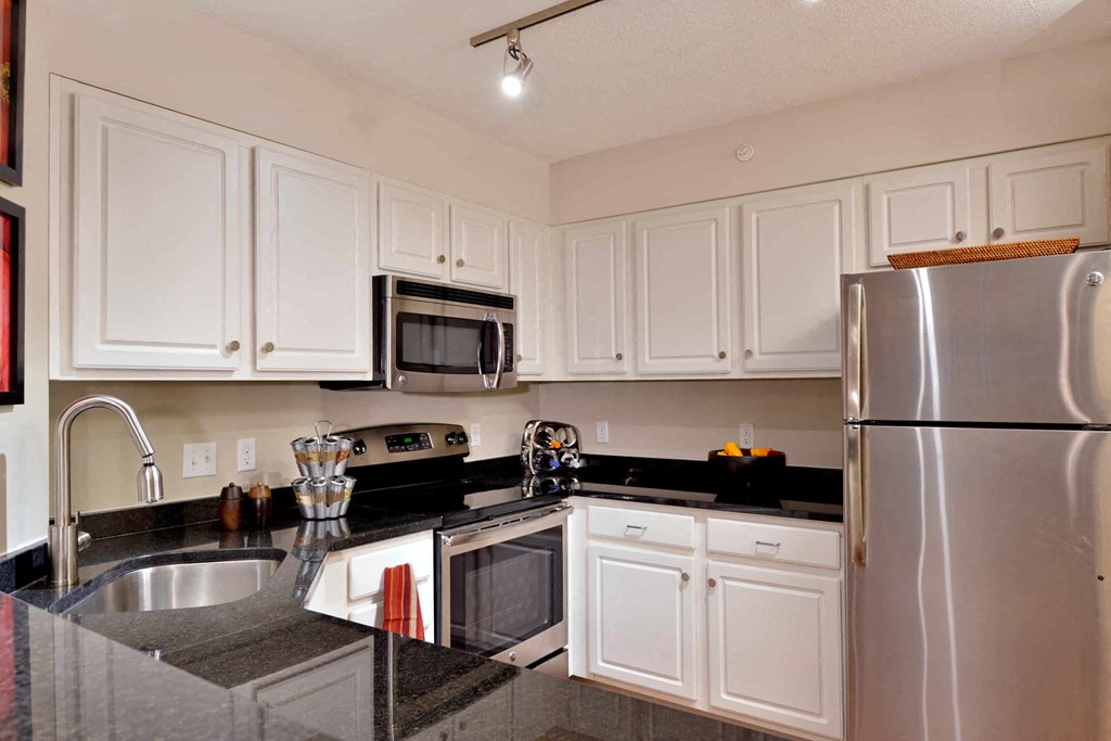 A kitchen with white cabinets and a black counter top.