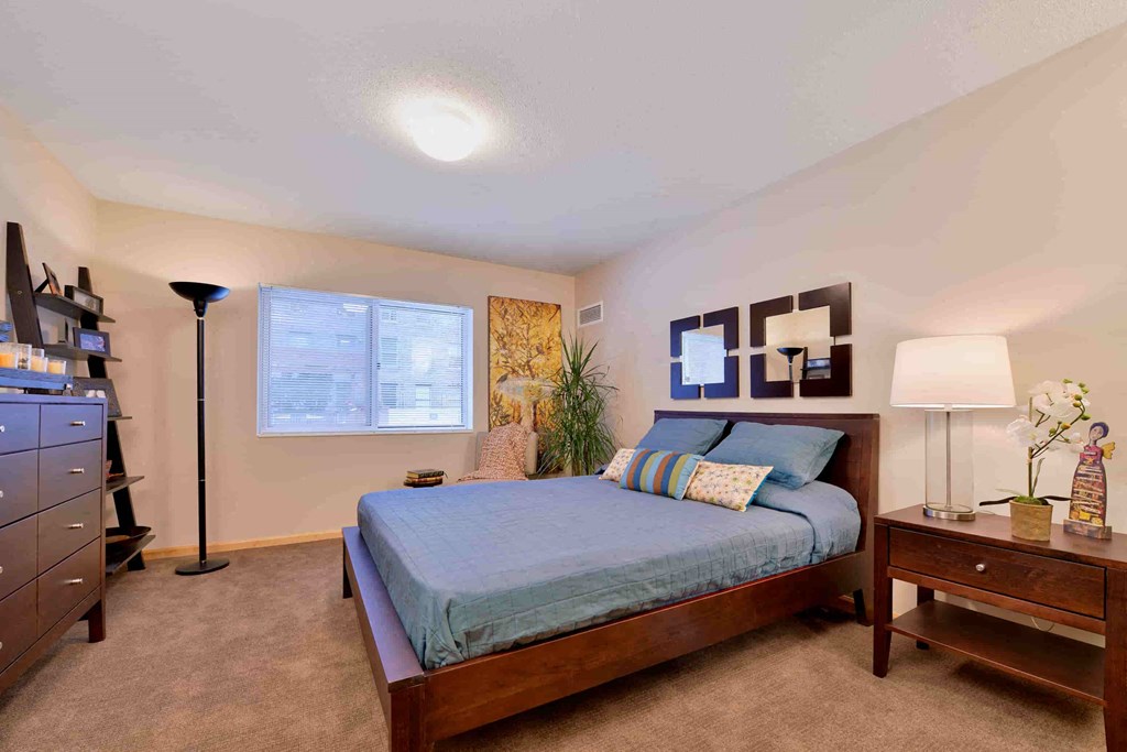 A bedroom with a bed, nightstand, and lamp.