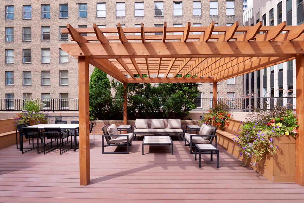 A wooden pergola over a patio with furniture.