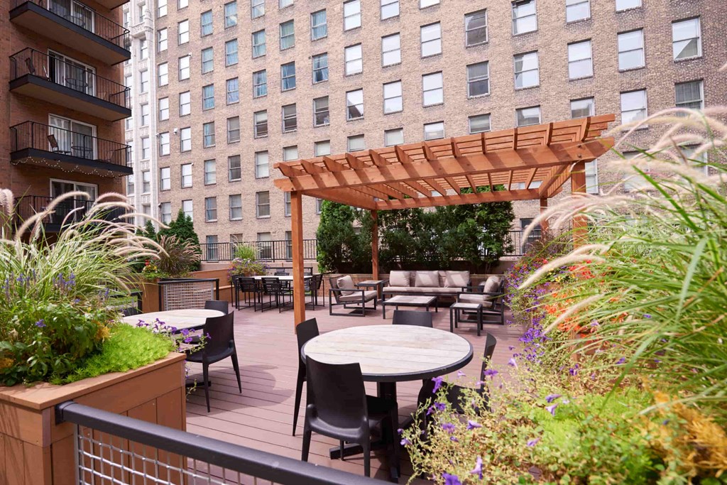 A wooden pergola is over a table surrounded by chairs.