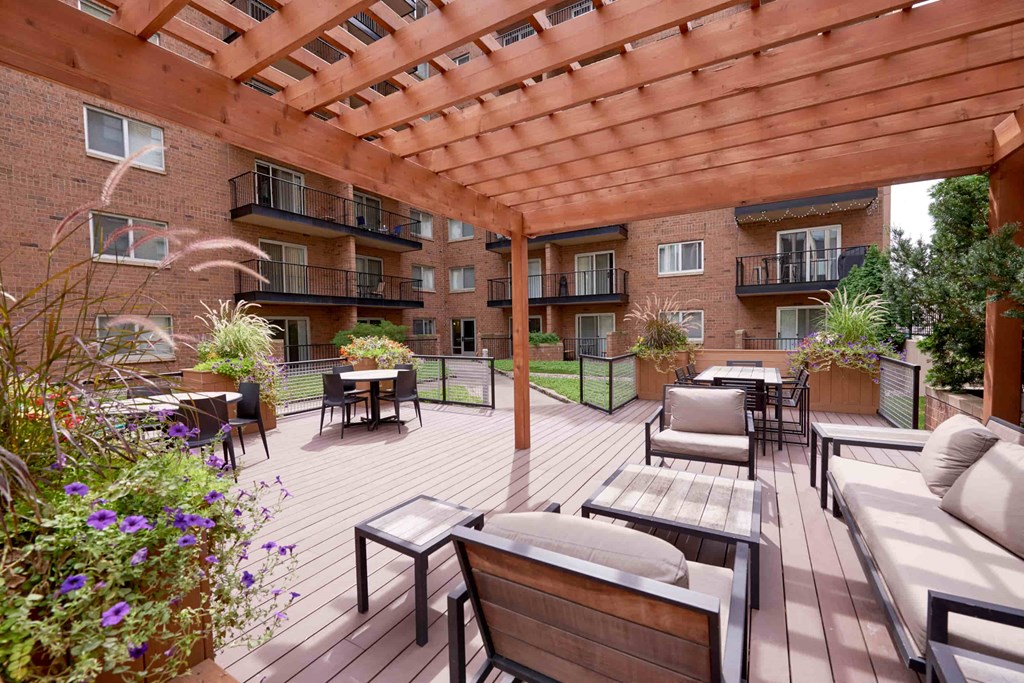A wooden patio with a pergola and furniture.