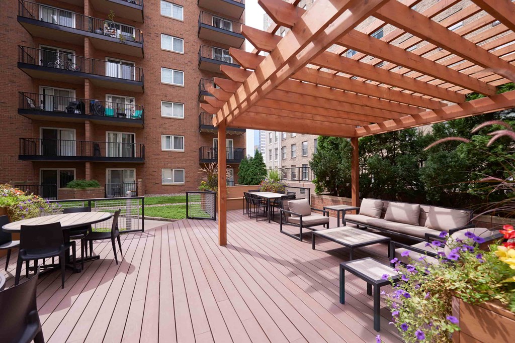 A wooden pergola is over a patio with a table and chairs.