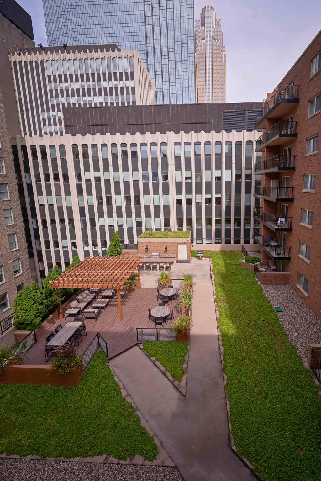 A courtyard surrounded by buildings with a wooden pergola and furniture.