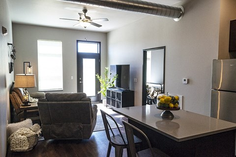 A modern kitchen with a grey chair and a table with a bowl of fruit on it.