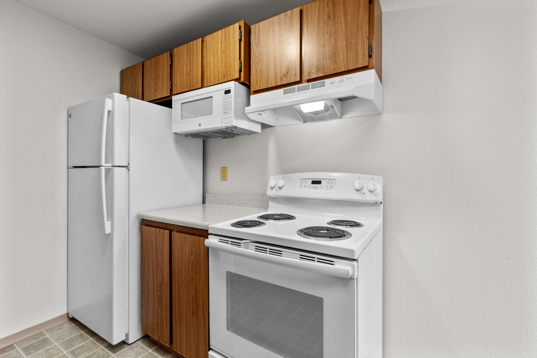 a kitchen with white appliances and wood cabinets and a refrigerator