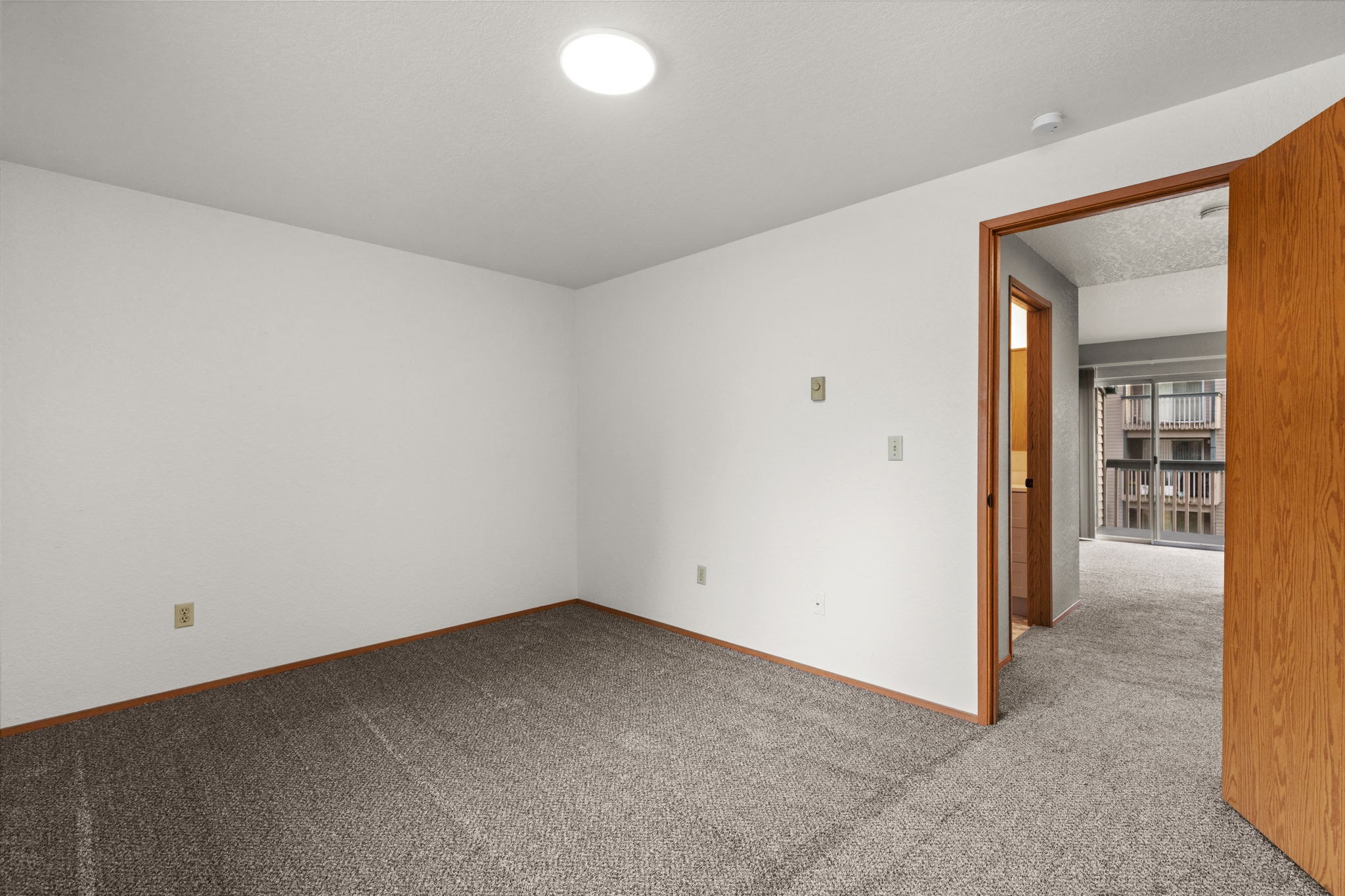 a living room with carpet and a door to a hallway