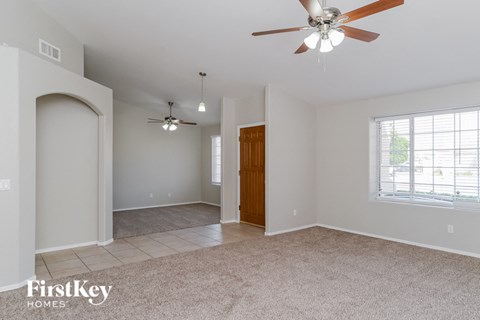 an empty living room with a ceiling fan and a door