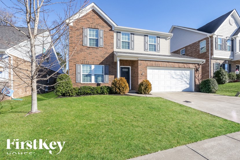 A house with a garage and a tree in front of it.