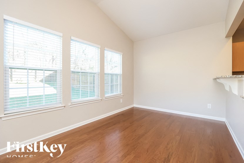 A room with wooden floors and three windows.