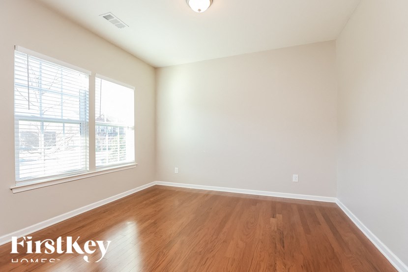 A room with wooden floors and a window with blinds.