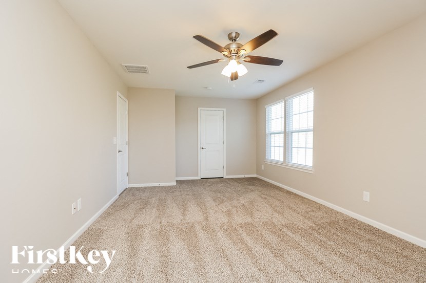 A spacious room with a ceiling fan and carpeted floor.