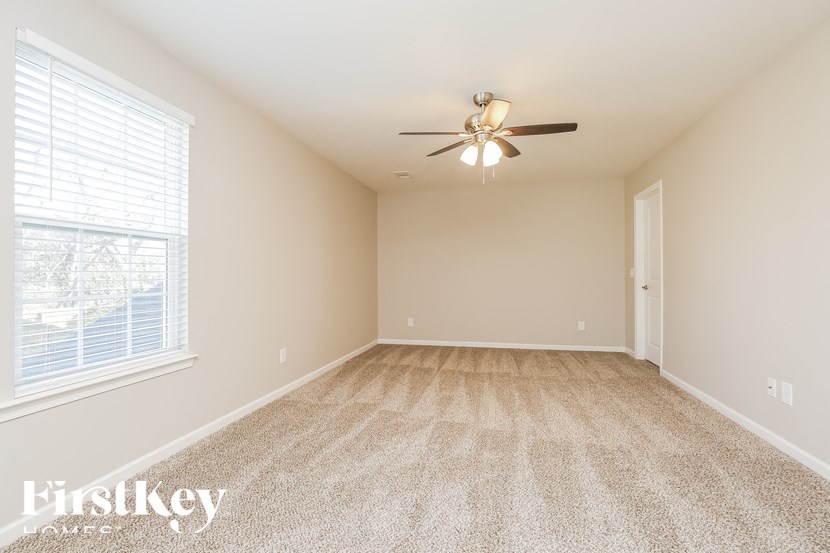 A spacious room with a carpeted floor and a ceiling fan.
