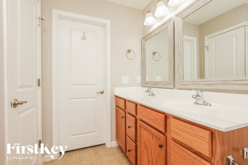 A bathroom with a white counter top and wooden cabinets.