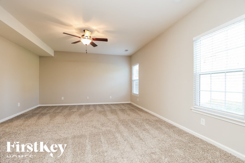 A spacious room with a carpeted floor and a ceiling fan.