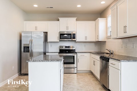 a white kitchen with stainless steel appliances and white cabinets