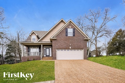 A brick house with a garage and a driveway in front.