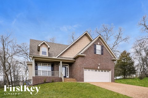 A house with a brick facade and a white garage door is for sale.