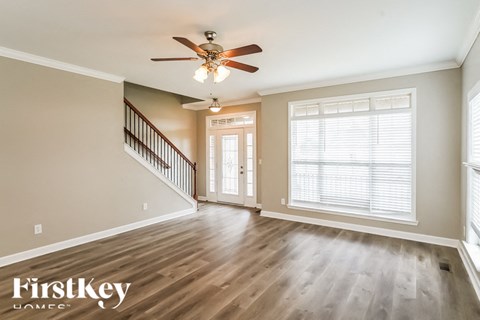 A spacious room with a staircase and a ceiling fan.